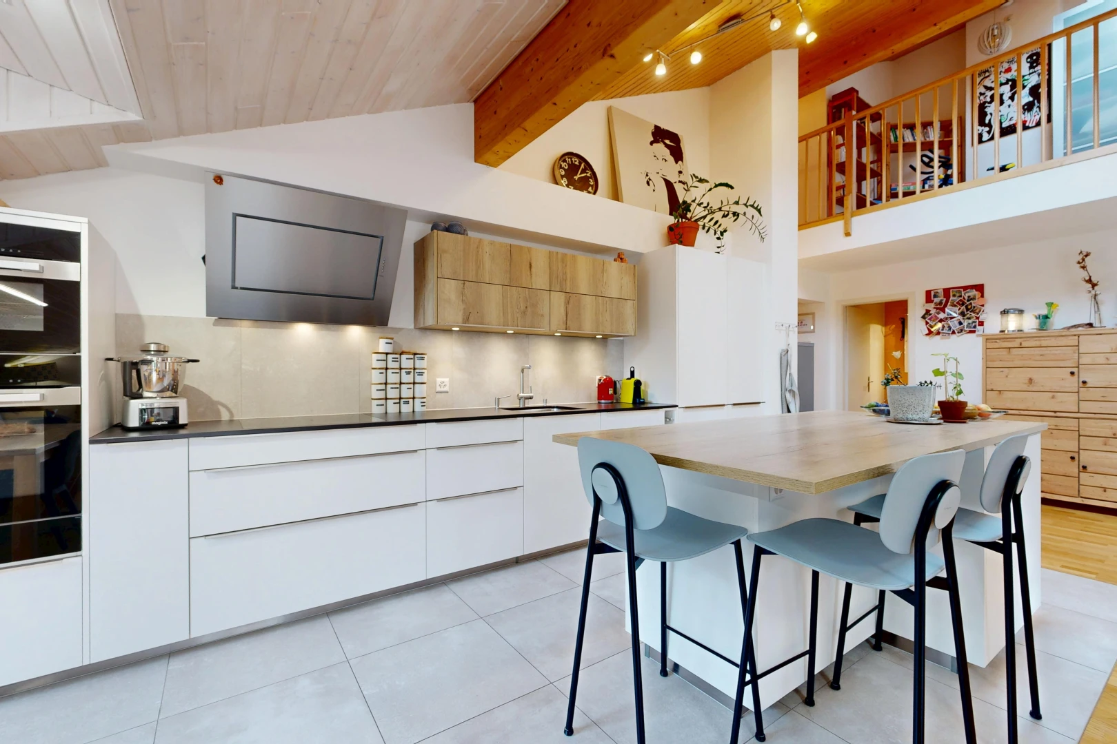 kitchen with two tone color scheme, modern cabinets, a breakfast bar, extractor fan, and a high wooden beamed ceiling