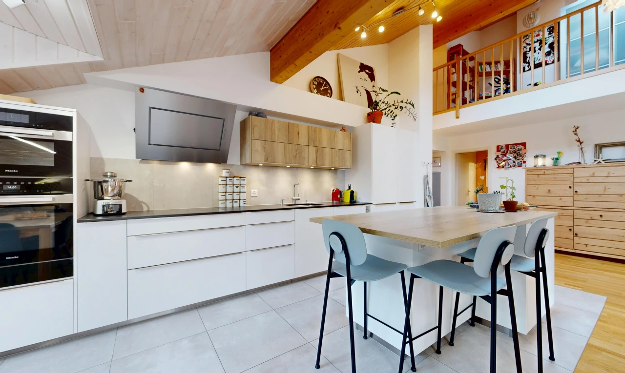 kitchen with two tone color scheme, modern cabinets, a breakfast bar, extractor fan, and a high wooden beamed ceiling