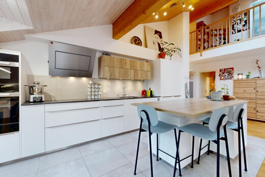 kitchen with two tone color scheme, modern cabinets, a breakfast bar, extractor fan, and a high wooden beamed ceiling