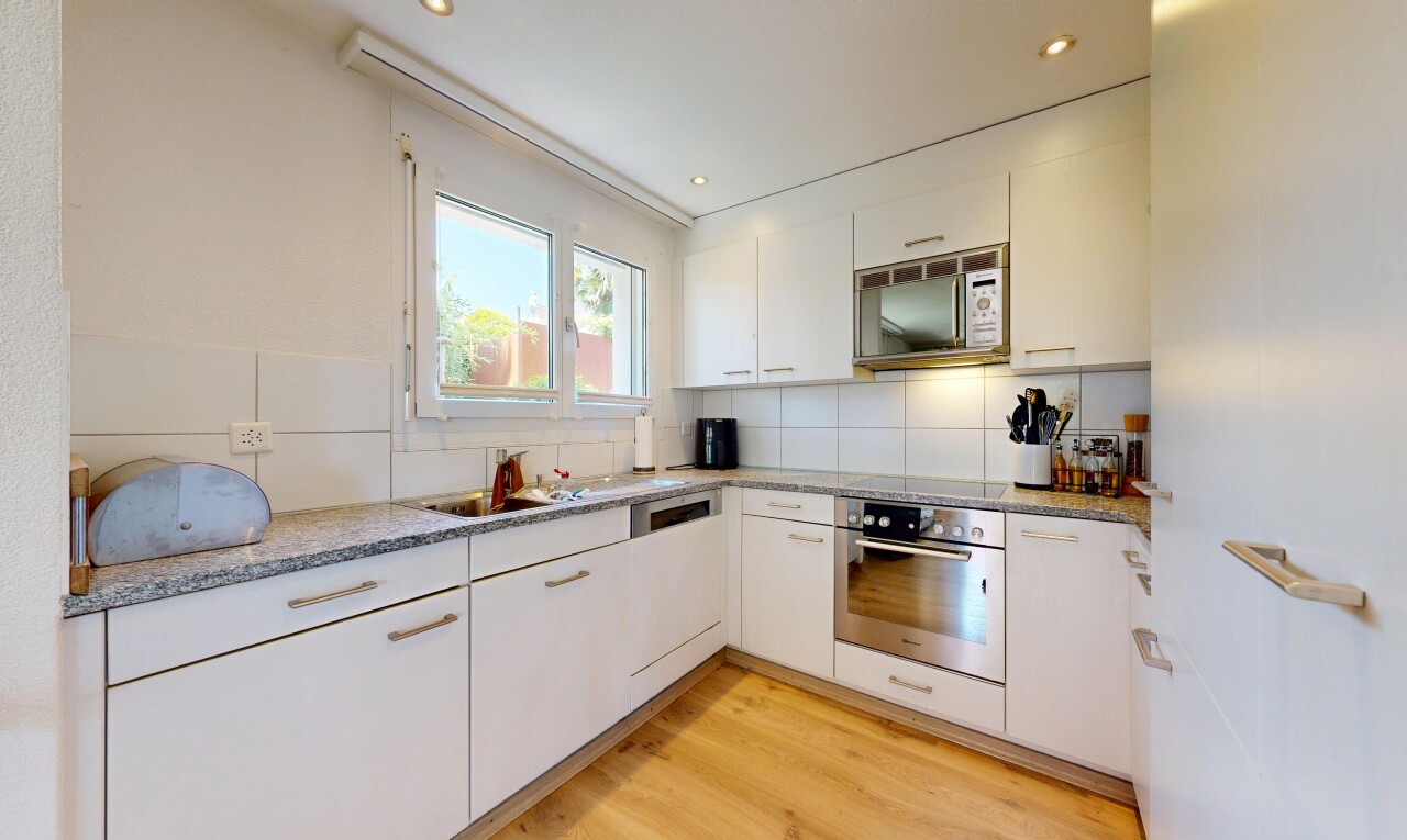 cuisine avec four, sol en finition bois, wood finish floor, light countertops, et light floor