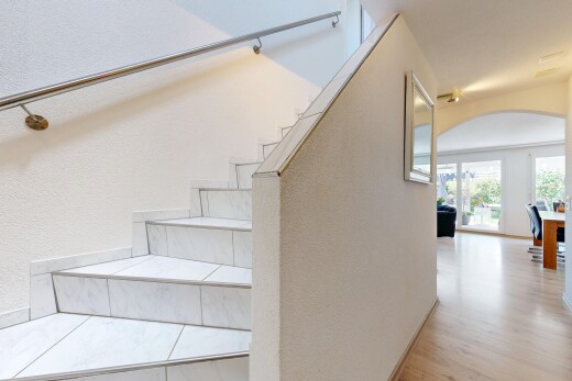 staircase with arched walkways, a textured wall, and wood finished floors