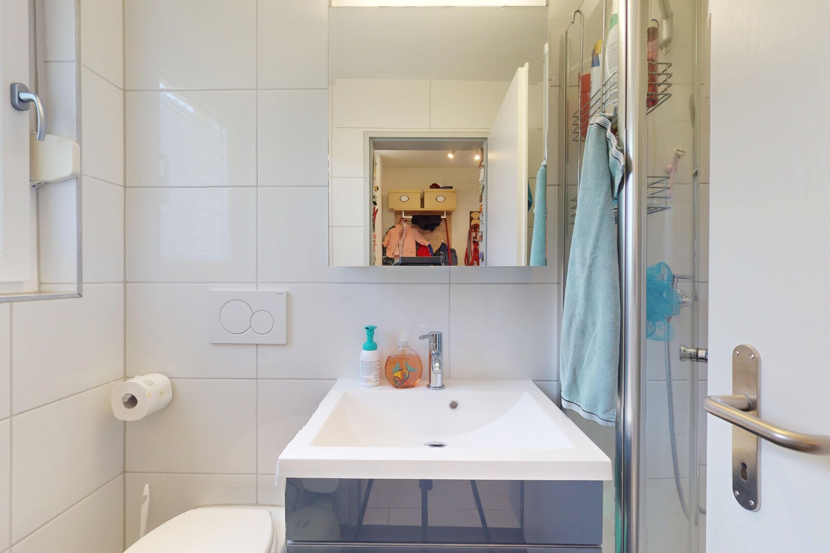salle de bains avec inside property, toilette, tile wall, mur en carrelage, et miroir