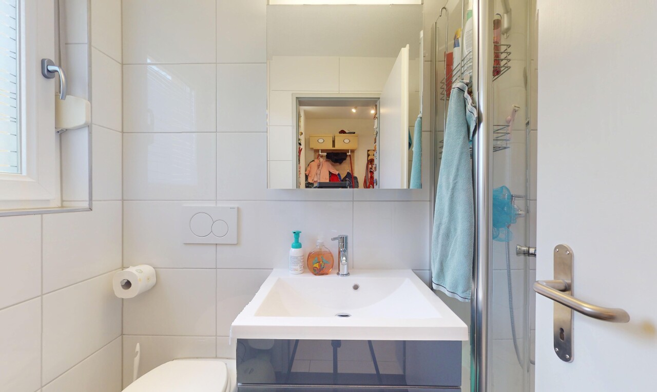 salle de bains avec inside property, toilette, tile wall, mur en carrelage, et miroir