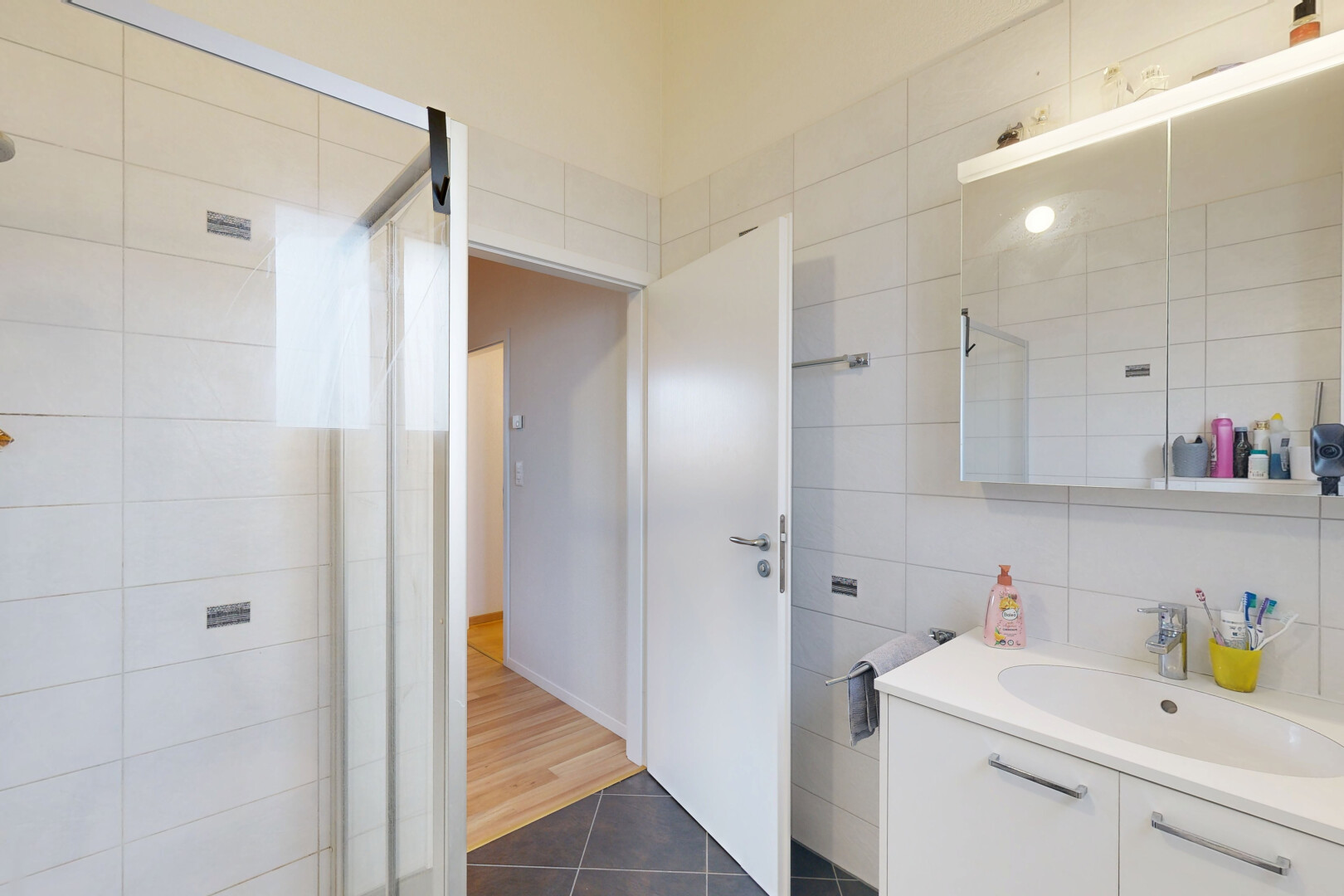 salle de bains avec douche, évier, miroir, salle de bain complète, et tile wall
