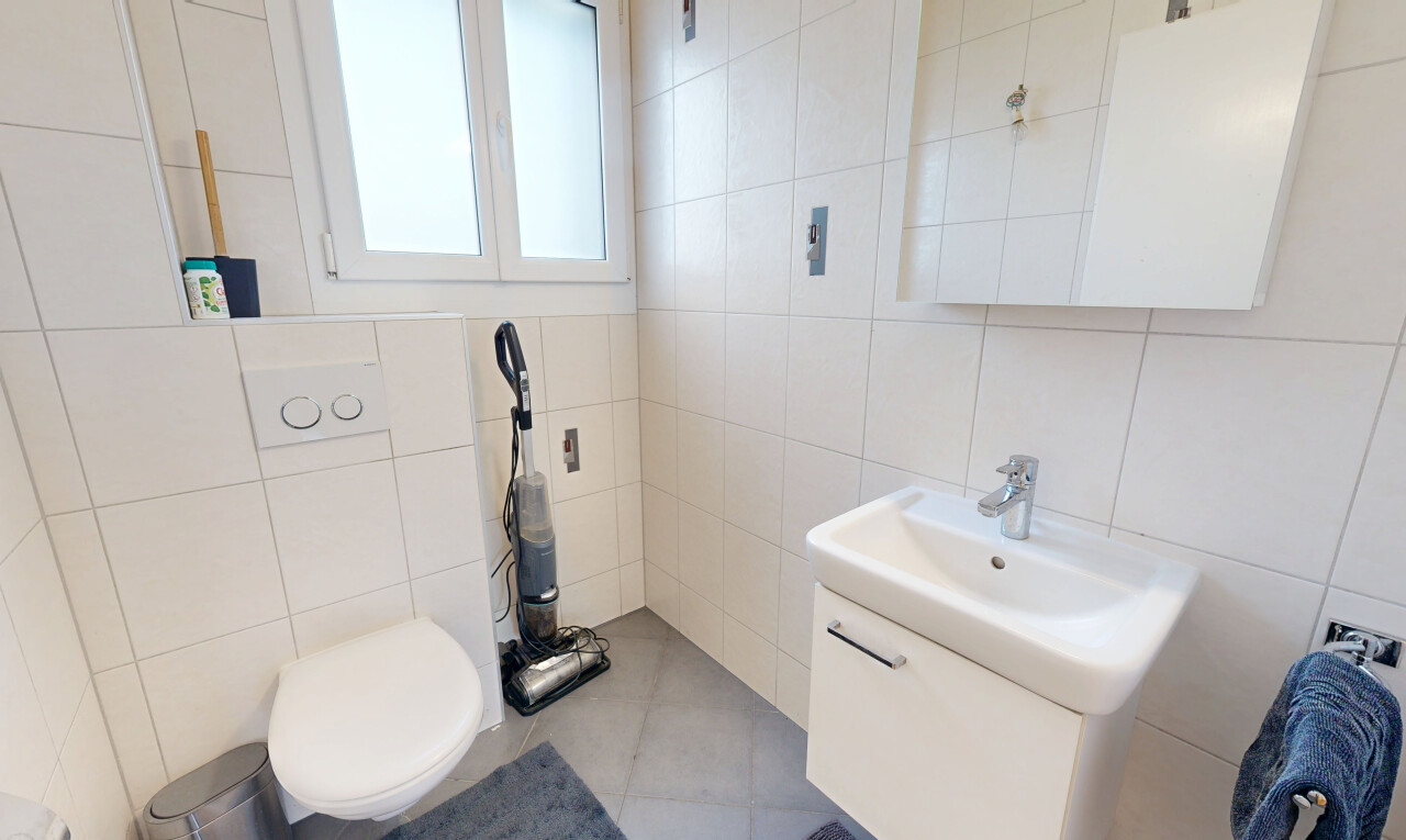 salle de bains avec mur en carrelage, tile wall, lavabo (ou coiffeuse selon le contexte), miroir, et toilette