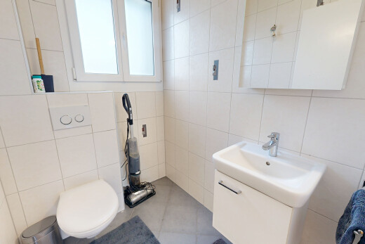 salle de bains avec mur en carrelage, tile wall, lavabo (ou coiffeuse selon le contexte), miroir, et toilette