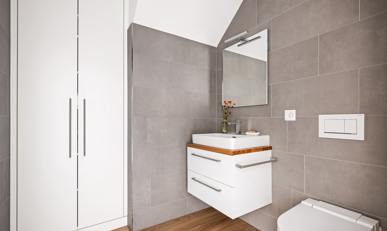 salle de bains avec miroir, lavabo (ou coiffeuse selon le contexte), tile wall, mur en carrelage, et inside property