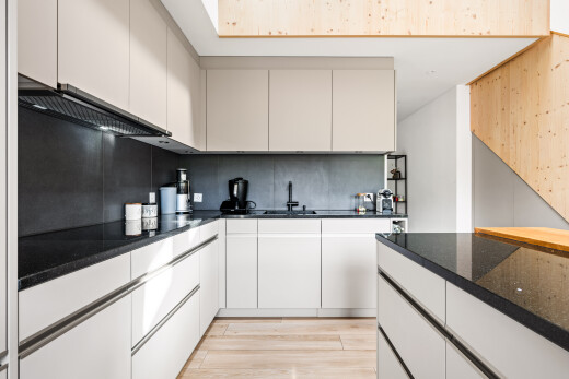 cuisine avec dark countertops, wood finish floor, sol en finition bois, inside property, et backsplash