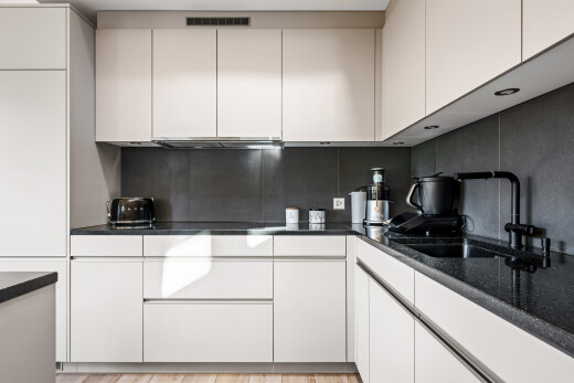 cuisine avec dark countertops, inside property, white cabinets, armoires blanches, et plans de travail en pierre