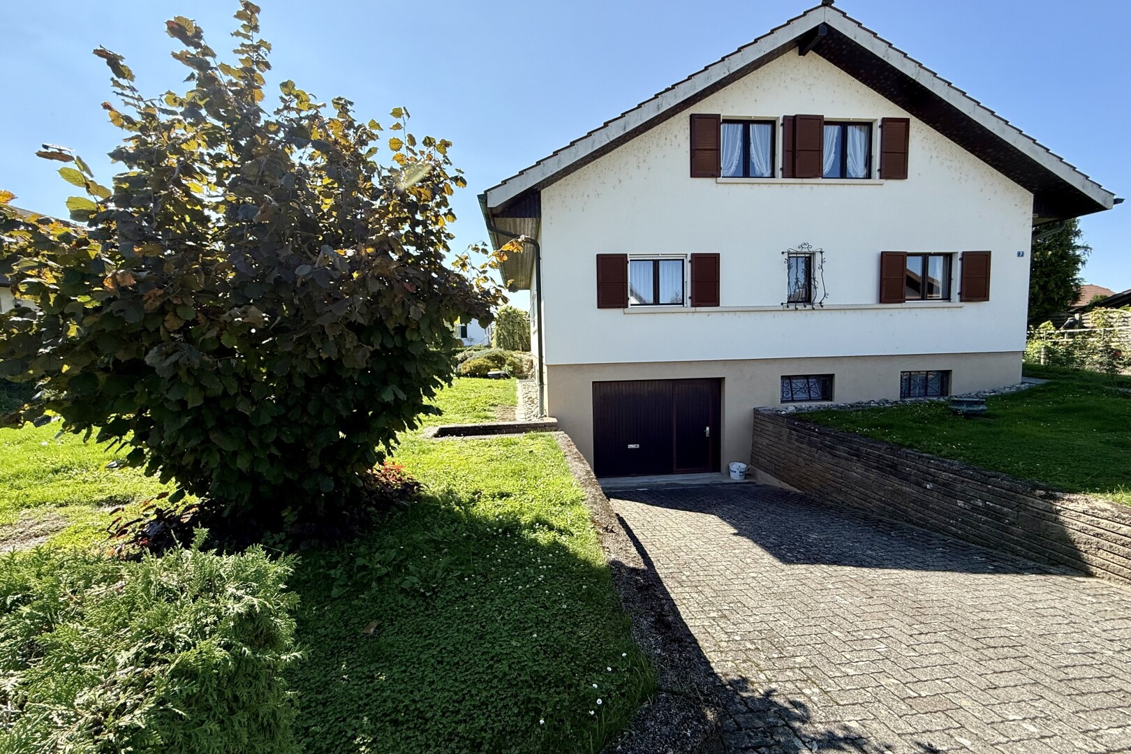 façade avec bardage en stuc, garage intégré, allée, property visible, et day time