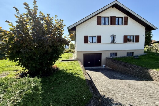 façade avec bardage en stuc, garage intégré, allée, property visible, et day time