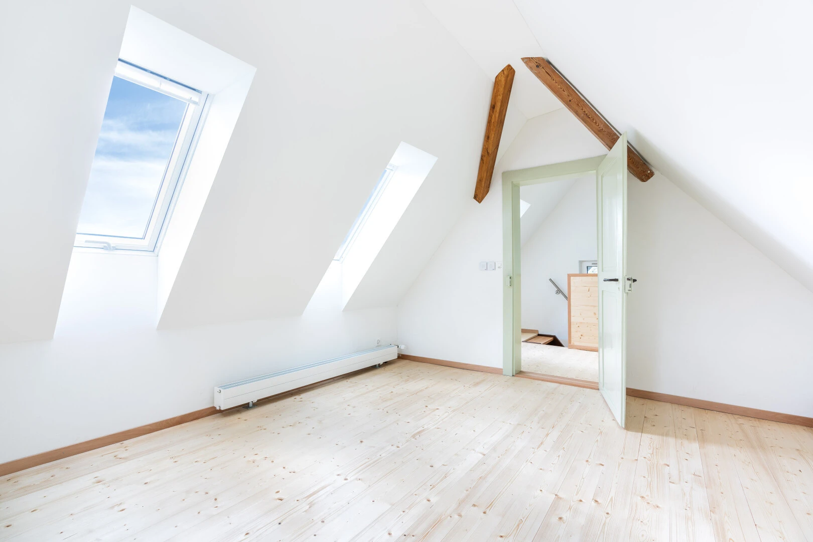 spare room with a baseboard radiator, light wood-style floors, and vaulted ceiling with beams