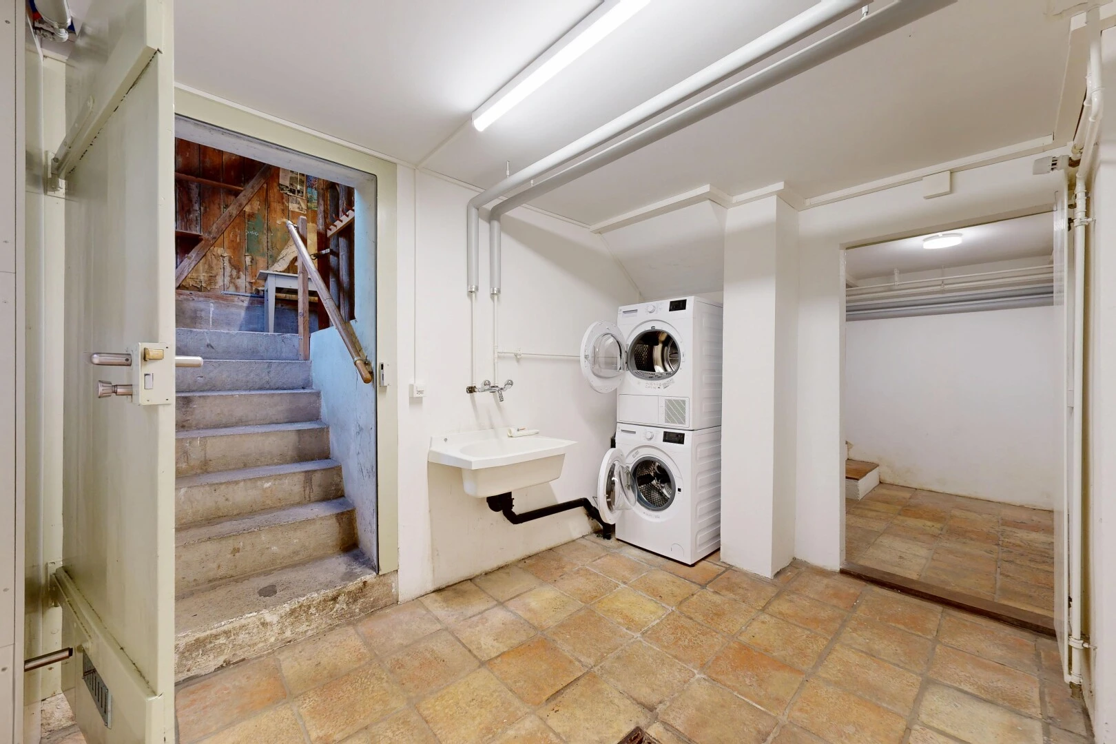 laundry area with stairs and stacked washer and dryer