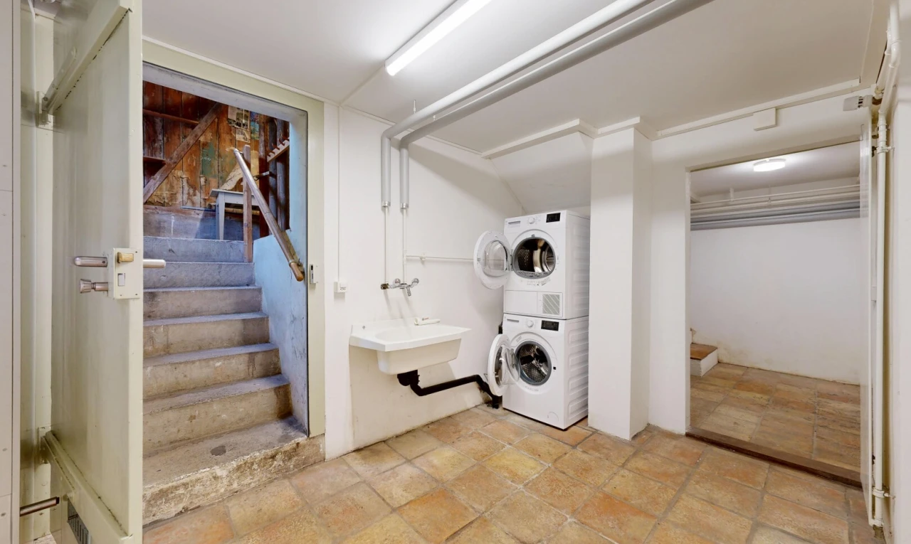 laundry area with stairs and stacked washer and dryer