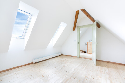 spare room with a baseboard radiator, light wood-style floors, and vaulted ceiling with beams