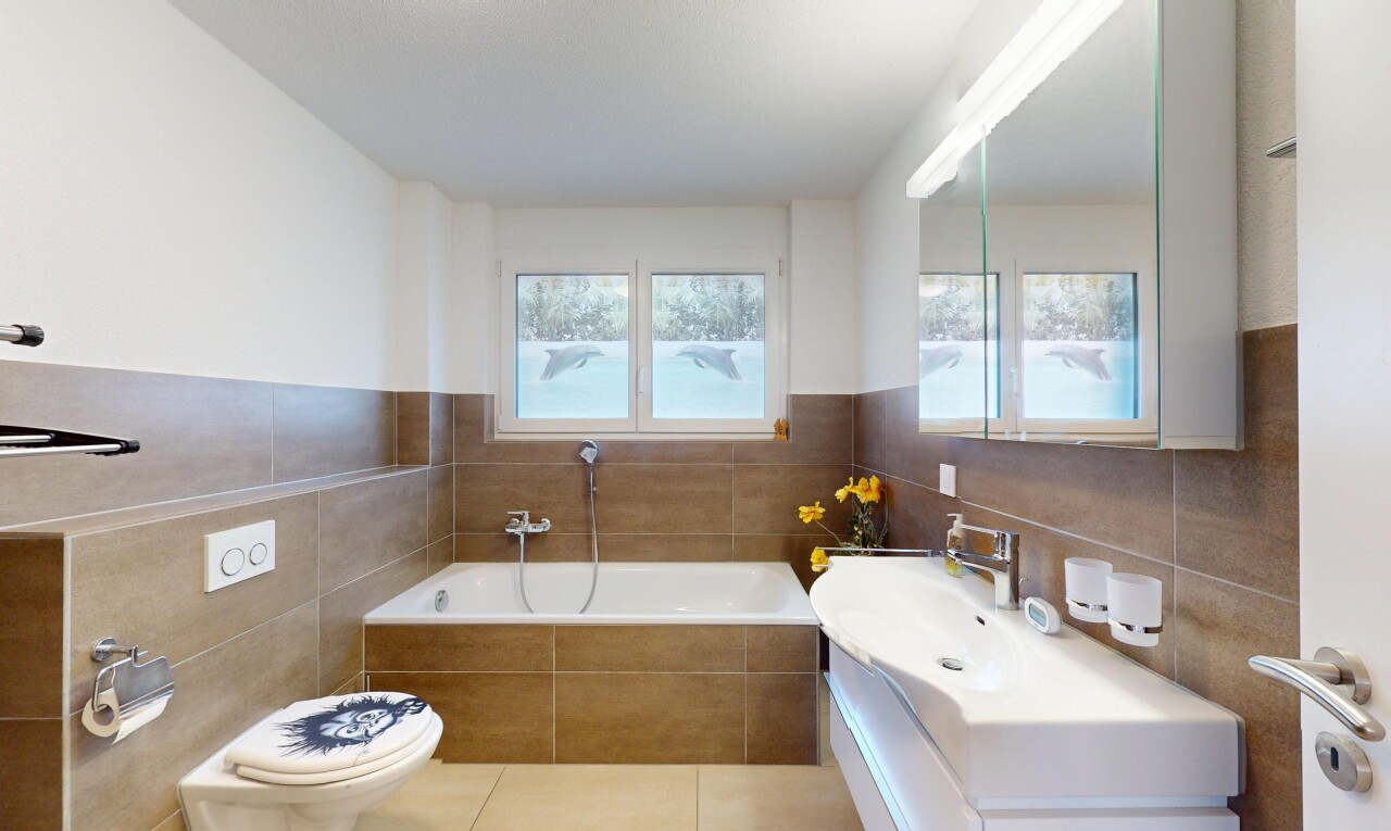 salle de bains avec mur en carrelage, toilette, lumière naturelle, salle de bain complète, et bain