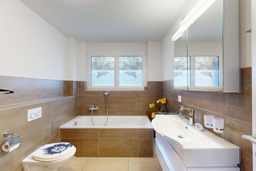salle de bains avec mur en carrelage, toilette, lumière naturelle, salle de bain complète, et bain