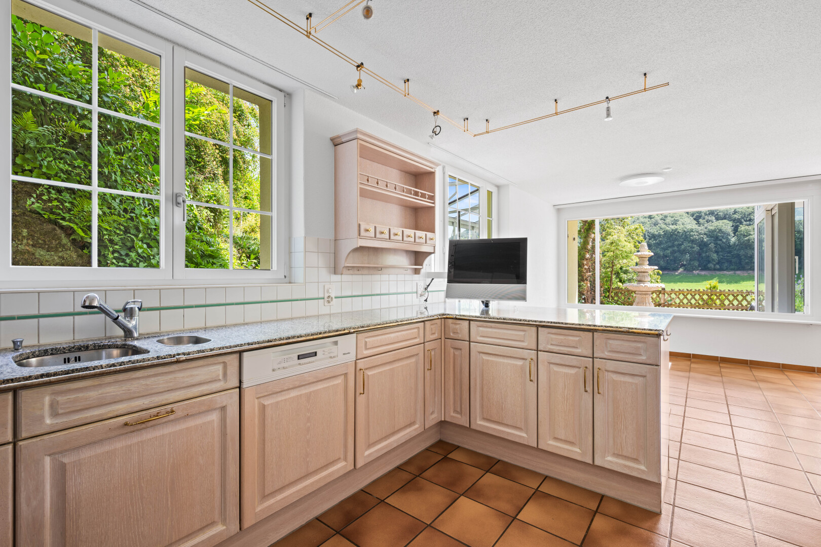 kitchen with light stone counters, healthy amount of natural light, tasteful backsplash, and rail lighting