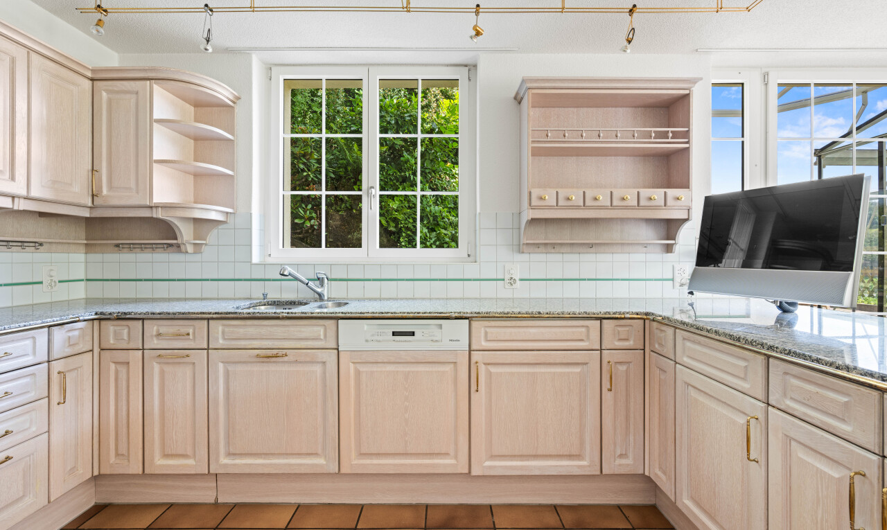 kitchen with open shelves, light wood finish cabinetry, light stone counters, and paneled dishwasher