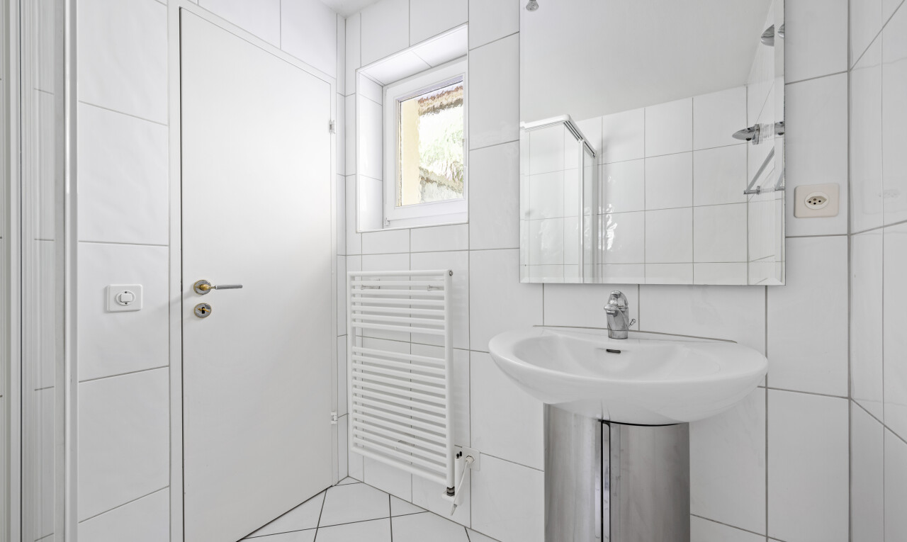 full bathroom featuring tile walls, radiator heating unit, tiled shower, and light tile patterned flooring