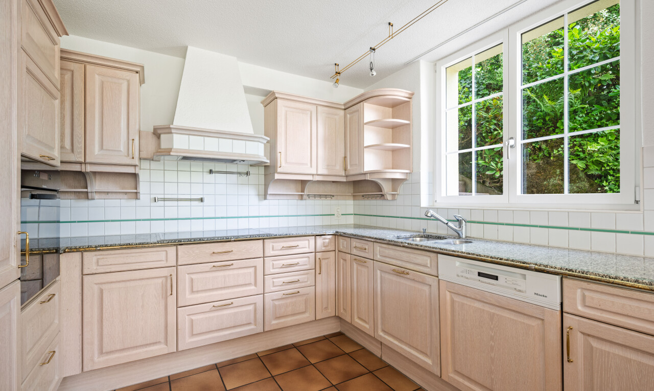 kitchen with light stone counters, open shelves, light wood finish cabinets, and dishwasher