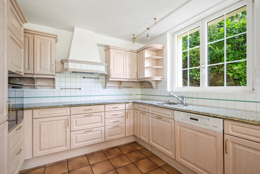 kitchen with light stone counters, open shelves, light wood finish cabinets, and dishwasher