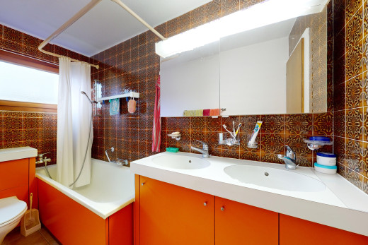 bad mit fliesenwand, spiegel, toilette, und kombiniertes bad / dusche