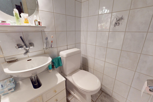 bad mit fliesenwand, waschbecken, spiegel, küchenrückwand beim herd, und toilette