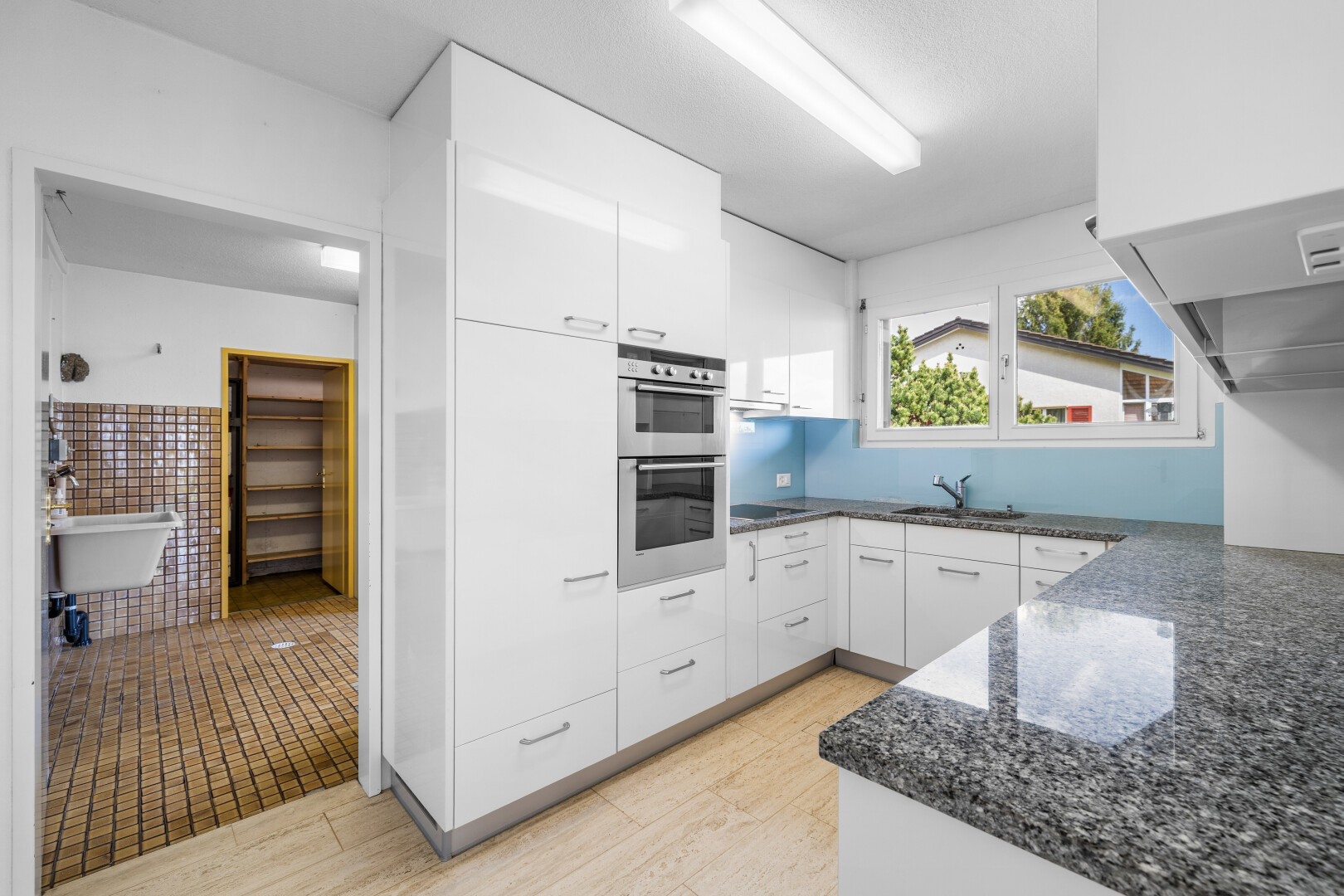 cuisine avec dark countertops, armoires blanches, white cabinets, light floor, et plans de travail en pierre