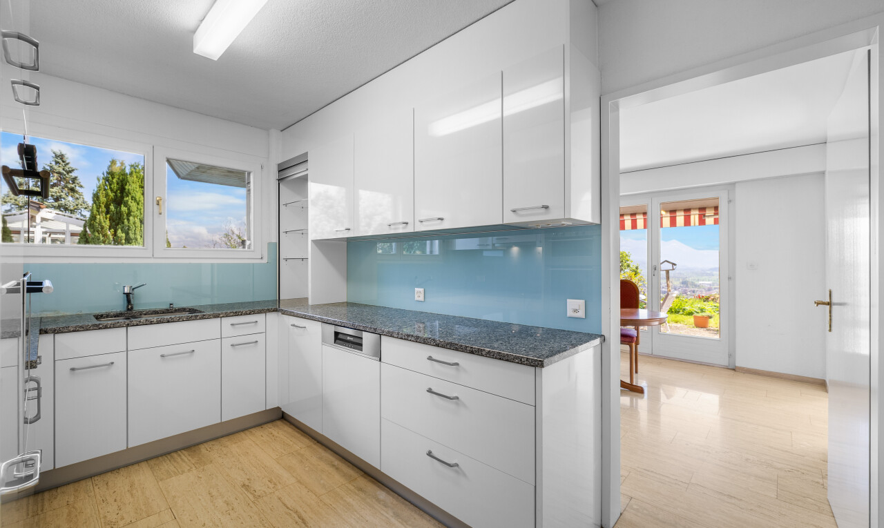 cuisine avec day time, dark countertops, white cabinets, armoires blanches, et light floor