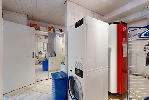 laundry area featuring light tile patterned floors, stacked washer and clothes dryer, and wooden ceiling