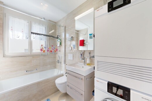 salle de bains avec miroir, lavabo (ou coiffeuse selon le contexte), salle de bain complète, toilette, et mur en carrelage