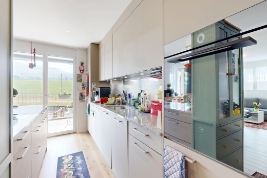 cuisine avec light countertops, sol en finition bois, wood finish floor, light floor, et armoires blanches