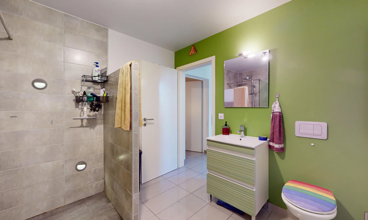 bathroom with a tile shower, tile patterned flooring, vanity, and toilet
