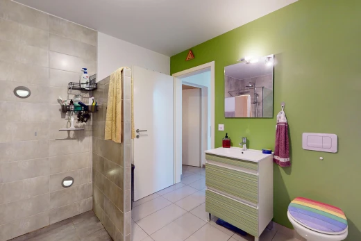 bathroom with a tile shower, tile patterned flooring, vanity, and toilet