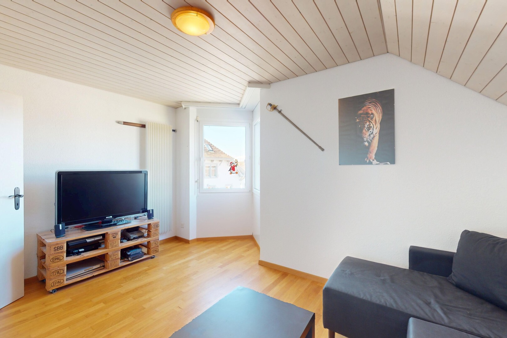 salon avec lumière naturelle, télévision, cloison sèche, plafond en bois, et sol en finition bois