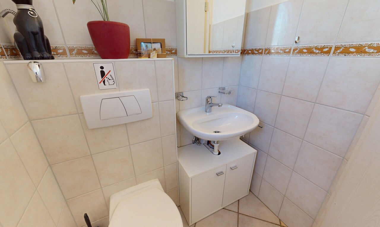 salle de bains avec miroir, mur en carrelage, toilette, et évier