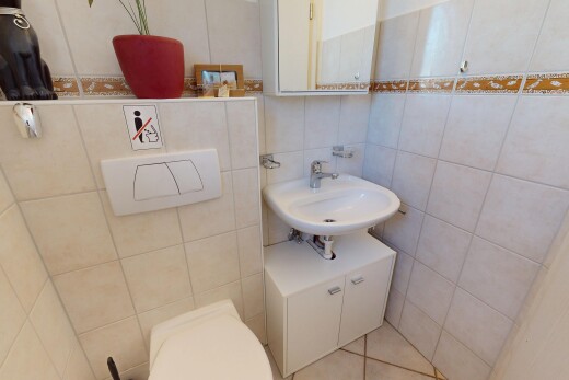 salle de bains avec miroir, mur en carrelage, toilette, et évier