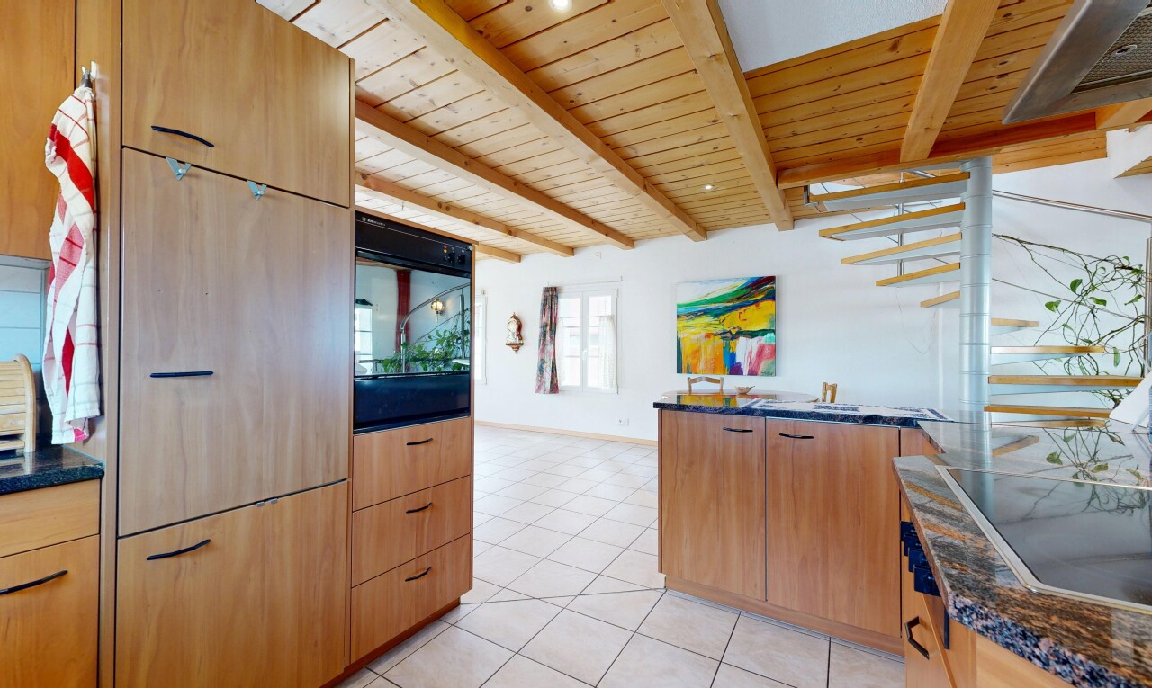 cuisine avec dark countertops, light floor, armoires marron clair, light brown cabinets, et cloison sèche