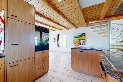 cuisine avec dark countertops, light floor, armoires marron clair, light brown cabinets, et cloison sèche