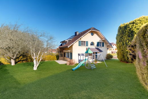 façade avec aire de jeux, pelouse, property visible, bardage en stuc, et day time