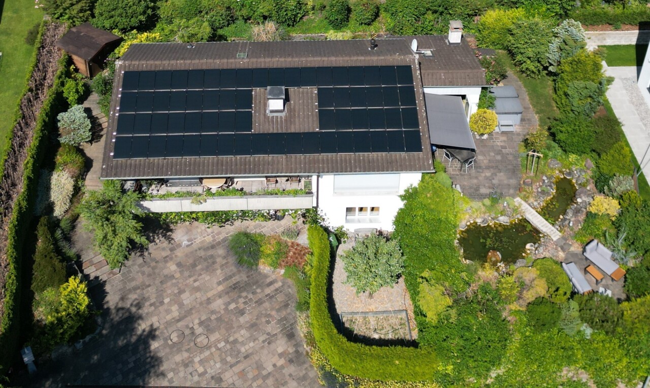 façade avec property visible, panneaux solaires, garage intégré, et bardage en stuc