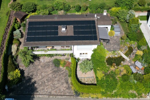 façade avec property visible, panneaux solaires, garage intégré, et bardage en stuc