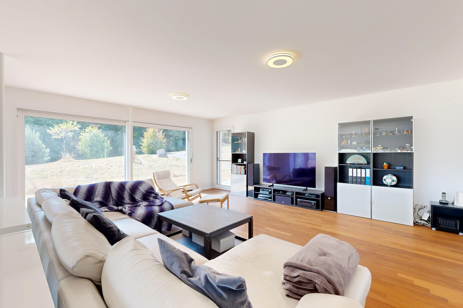 salon avec télévision, drywall, cloison sèche, wood finish floor, et sol en finition bois