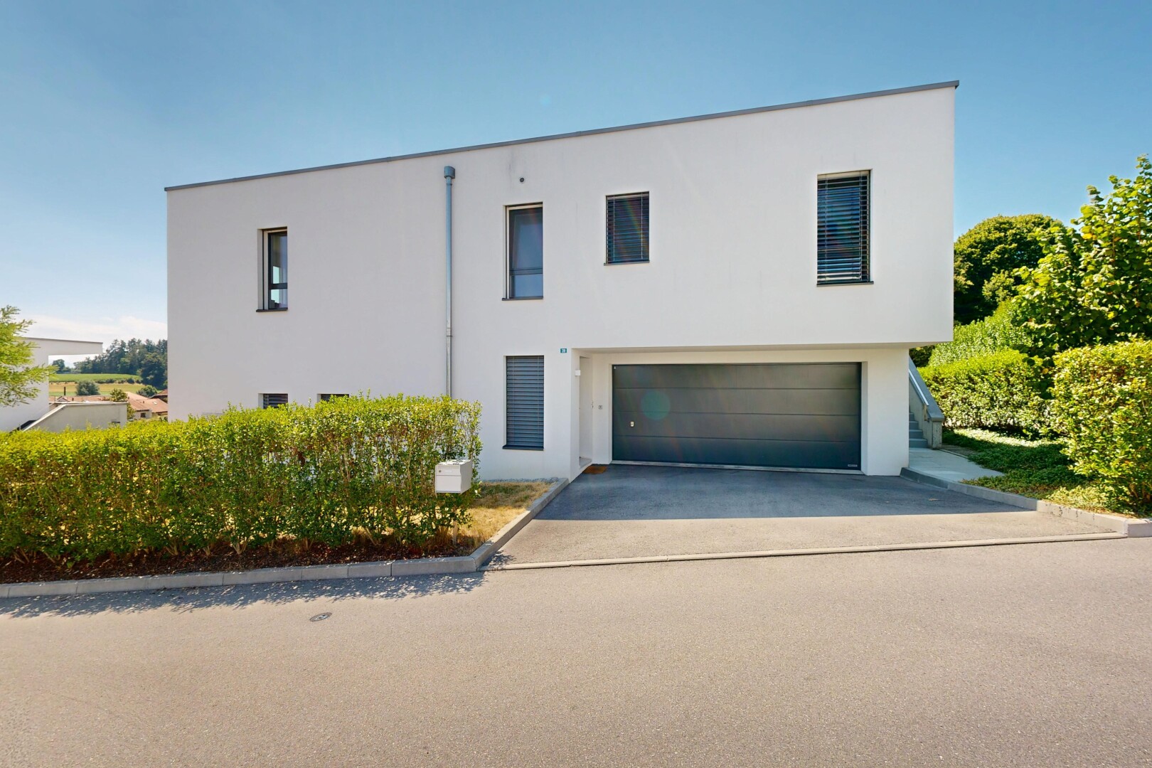 façade avec garage intégré, property visible, bardage en stuc, allée, et day time