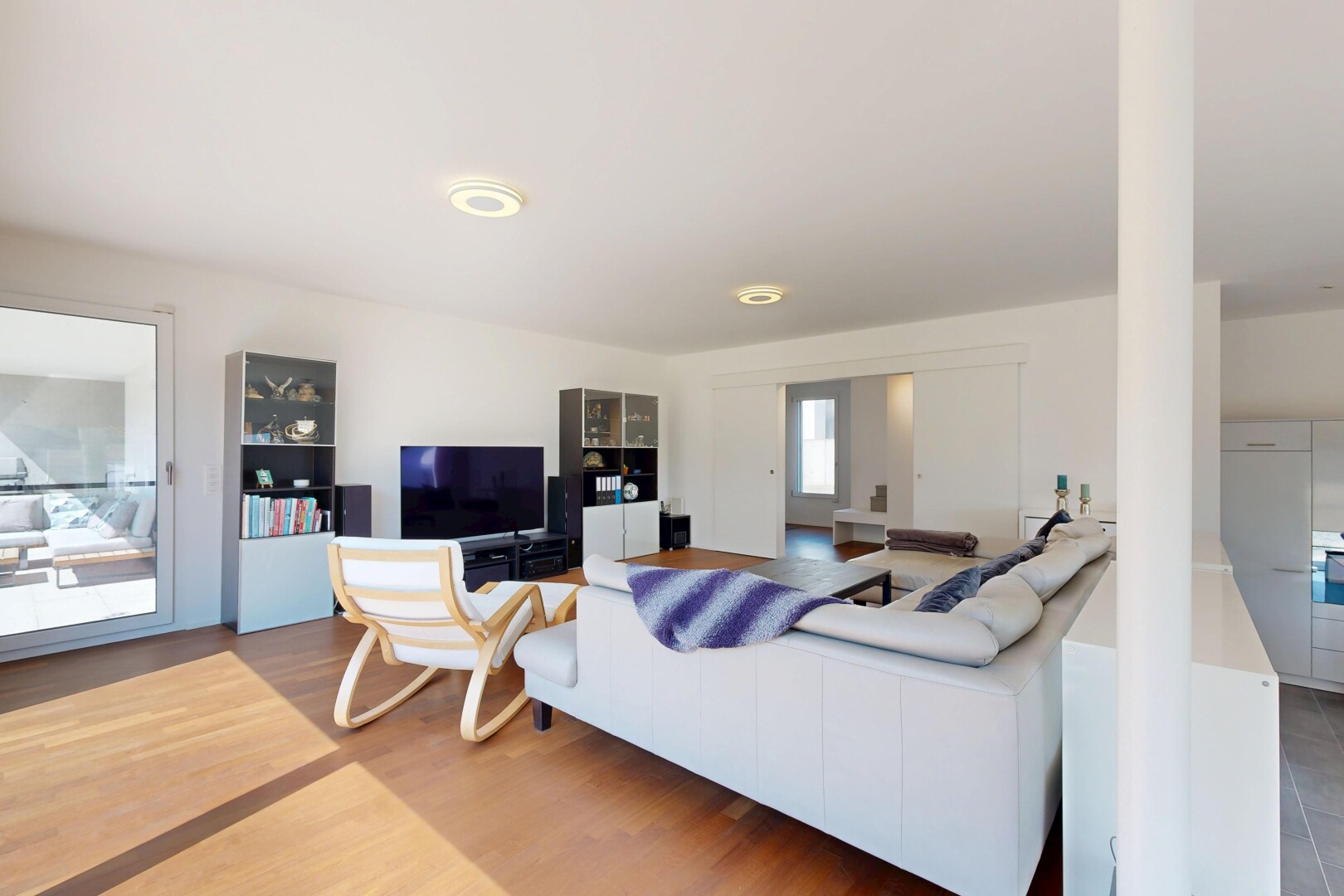 salon avec télévision, cloison sèche, drywall, sol en finition bois, et wood finish floor