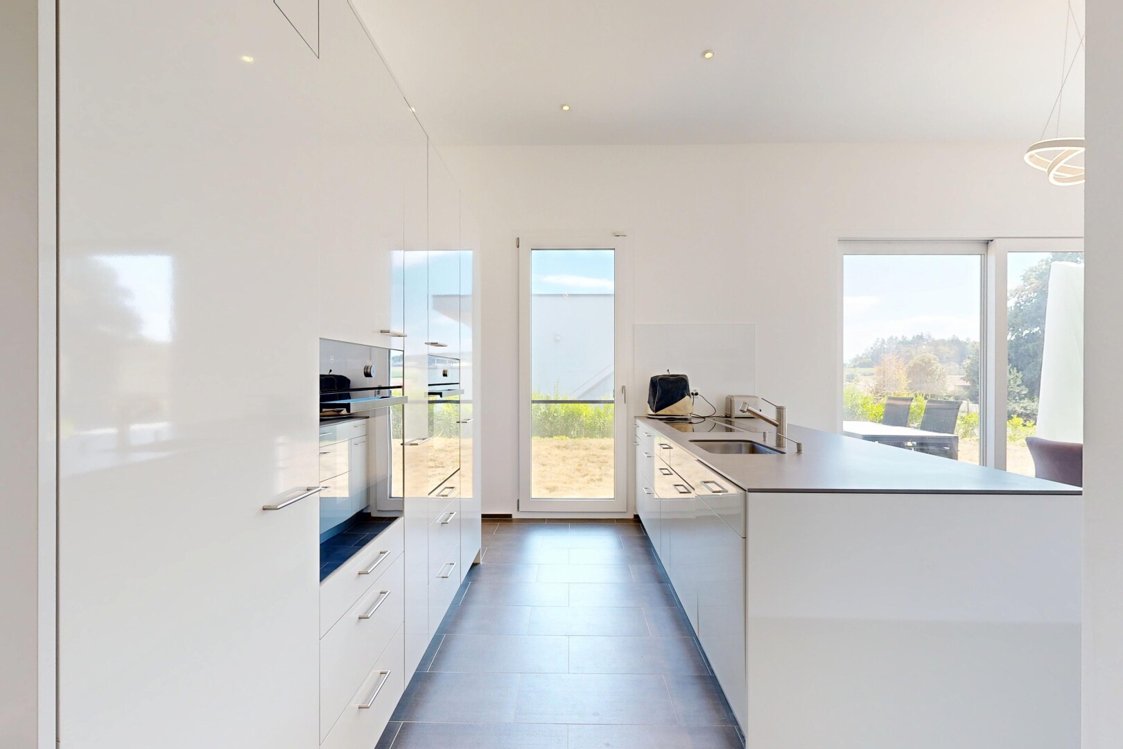 cuisine avec kitchen peninsula, péninsule de cuisine, lumière naturelle, dark floor, et flat panel cabinets
