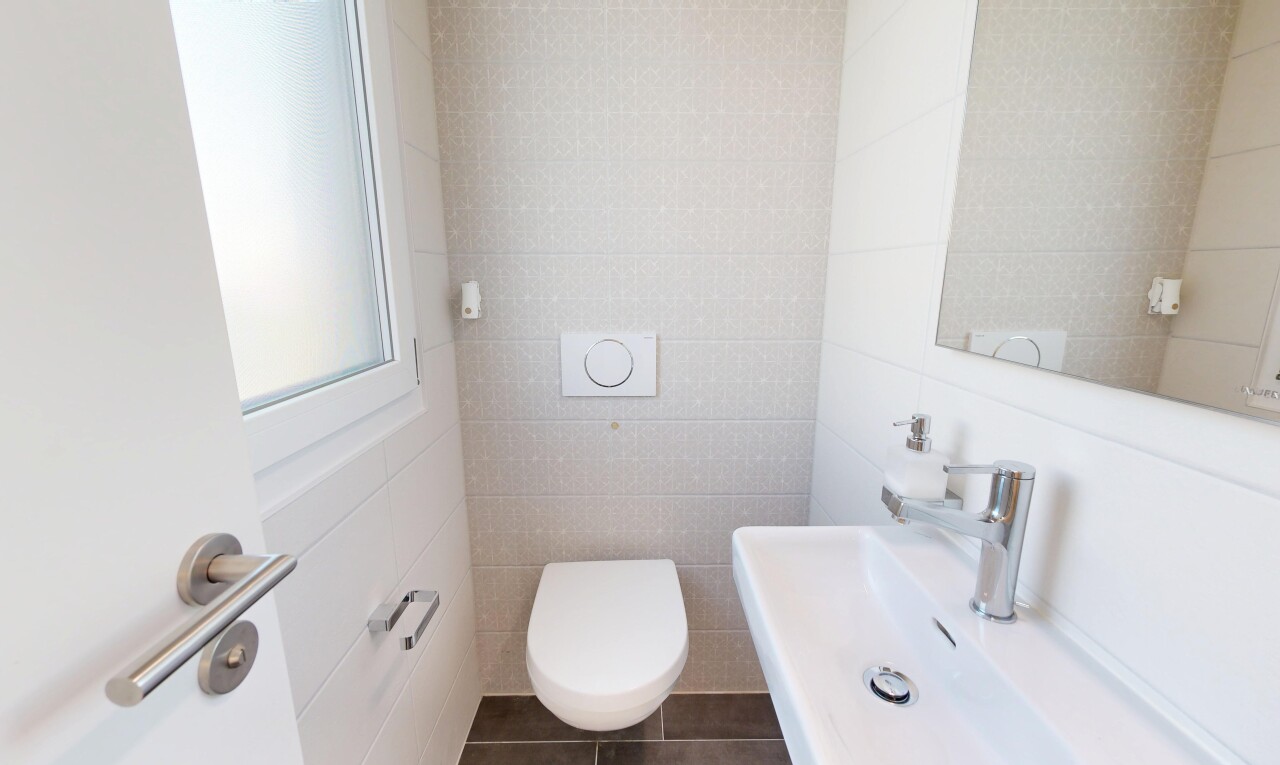 salle de bains avec mur en carrelage, tile wall, toilette, évier, et miroir