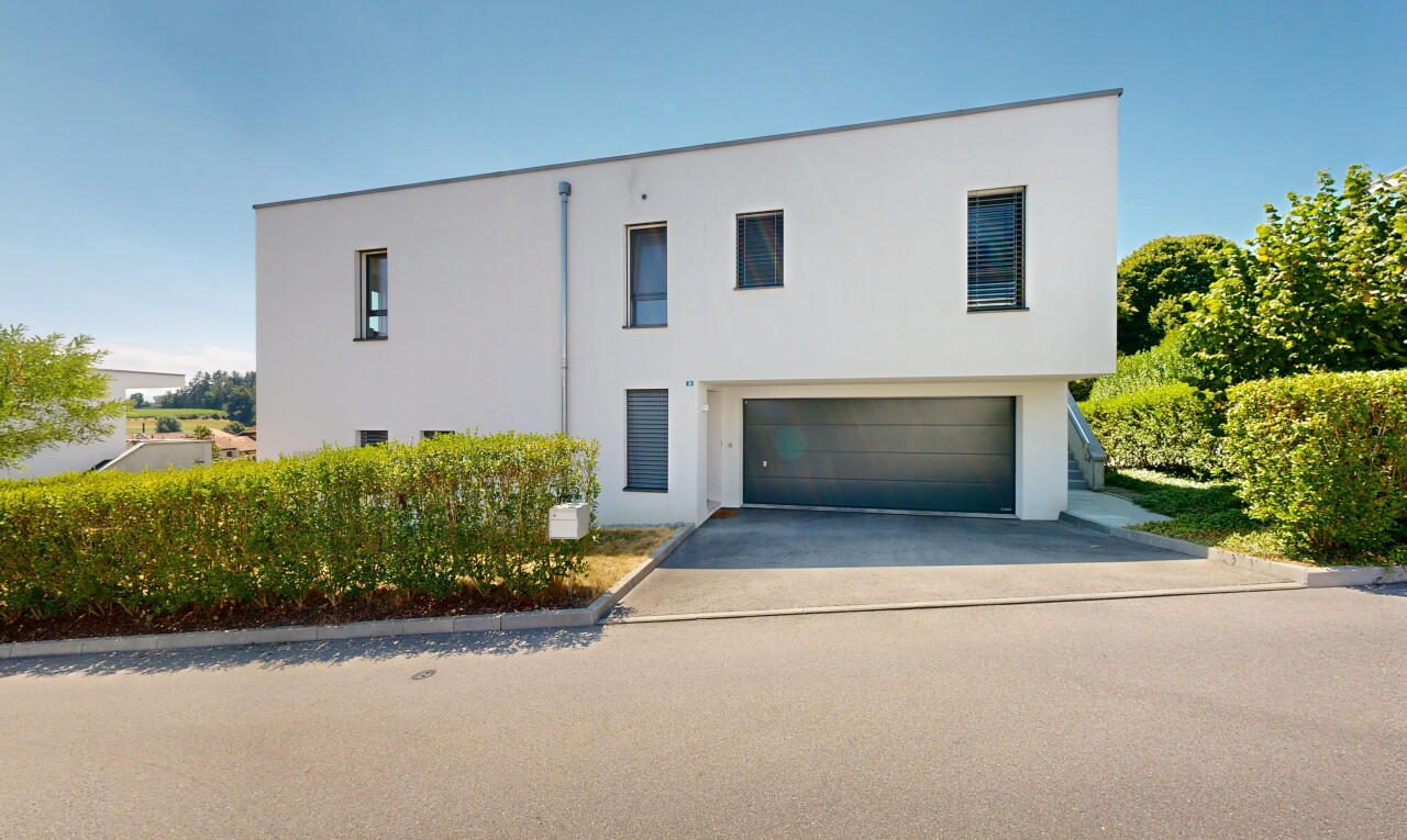 façade avec garage intégré, property visible, bardage en stuc, allée, et day time