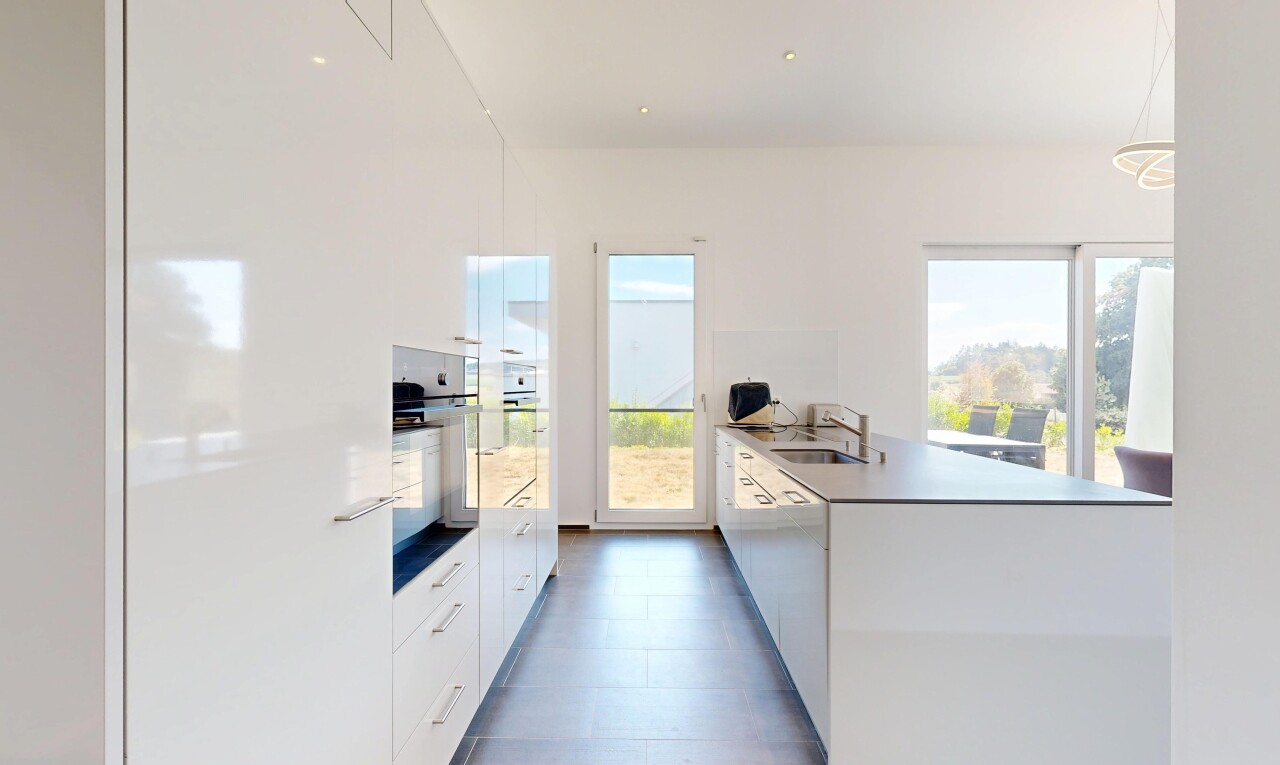 cuisine avec kitchen peninsula, péninsule de cuisine, lumière naturelle, dark floor, et flat panel cabinets